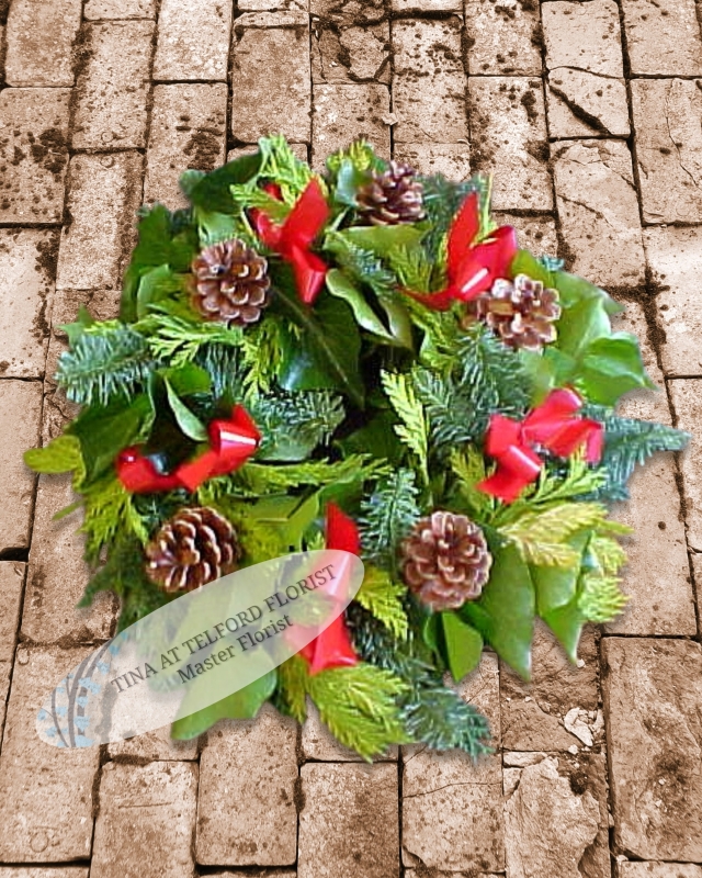 Festive wreath, adorned with white or red flowers, red berries, and bows. Vibrant greenery adds seasonal charm
