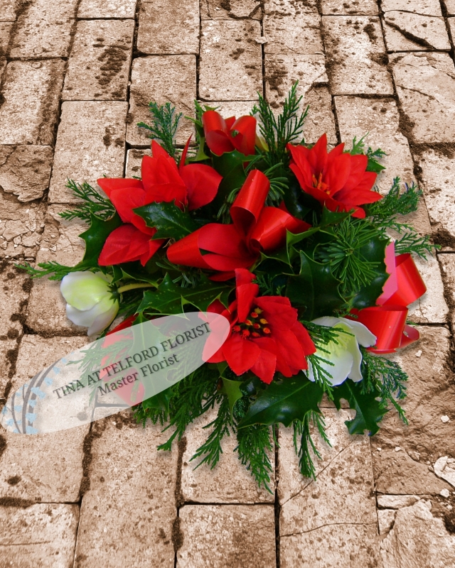 Festive posy arrangement with red ribbons and white flowers, surrounded by green foliage