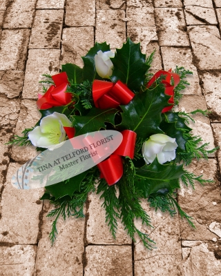 Festive posy arrangement with red ribbons and white flowers, surrounded by green foliage