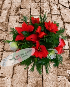 Festive posy arrangement with red ribbons and white flowers, surrounded by green foliage