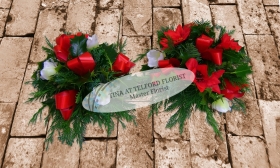 Festive posy arrangement with red ribbons and white flowers, surrounded by green foliage