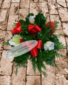 Festive posy arrangement with red ribbons and white flowers, surrounded by green foliage