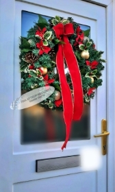 A festive wreath with red ribbons and ornaments hangs on a white door, accented with pine cones and greenery, evoking a cheerful holiday spirit.